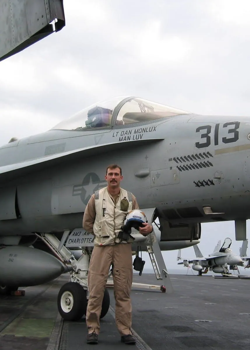 Lieutenant Dan Monlux standing before an F/A-18 with his name on the canopy rail