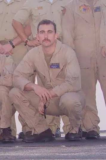 Dr. Monlux crouched on the flightline in a tan desert flight suit